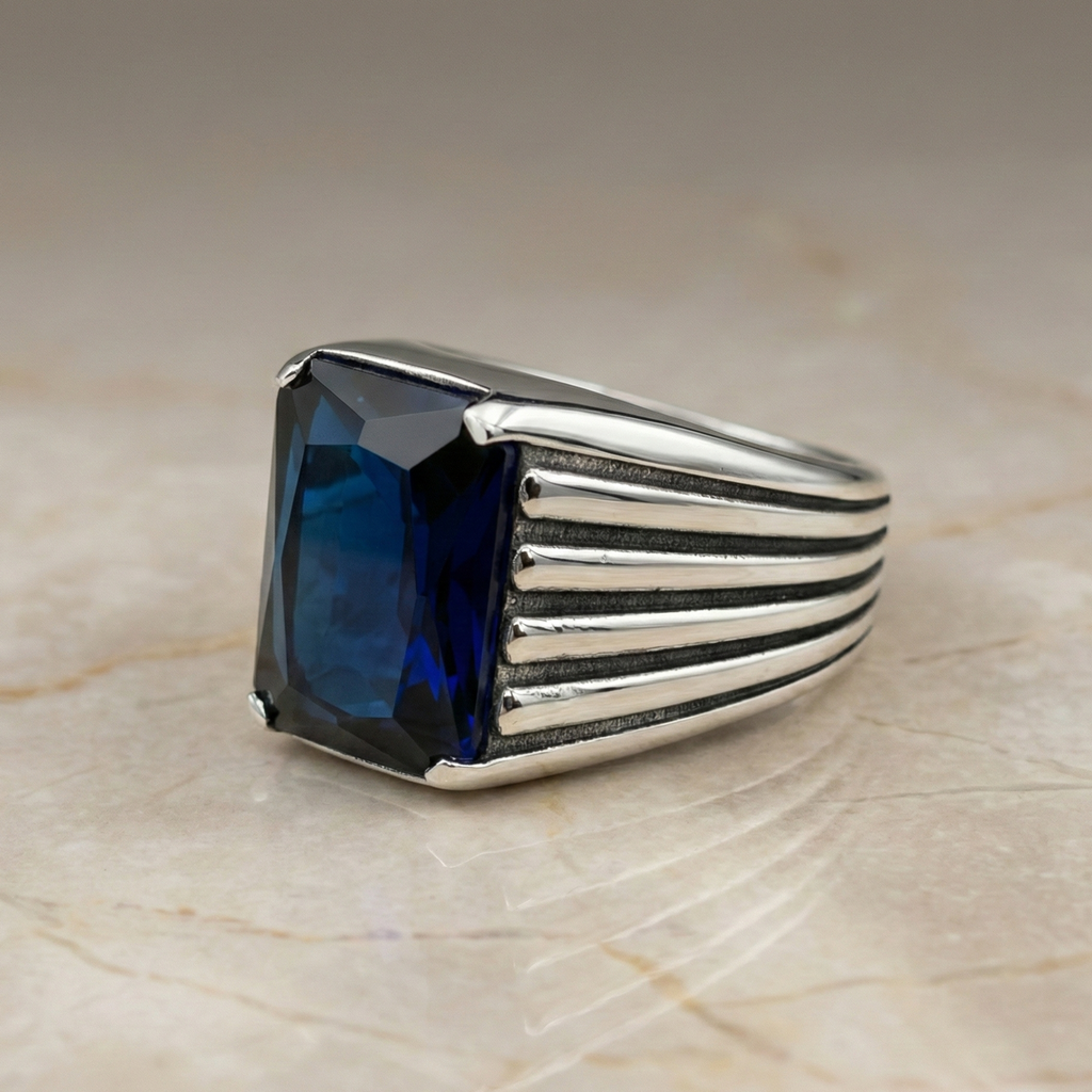 Silver ring with a blue gemstone on a beige marble surface
